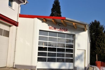 "Mein Lager" Außenansicht: eine weiße Lagerhalle mit Fensterfront und rotem Dach.