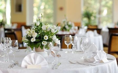 Elegant dekorierter runder Tisch für eine Hochzeit mit weißen Blumen und Kerzen.
