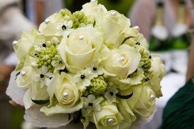 Nahaufnahme eines Blumenstraußes mit weißen Rosen und grünen Akzenten.