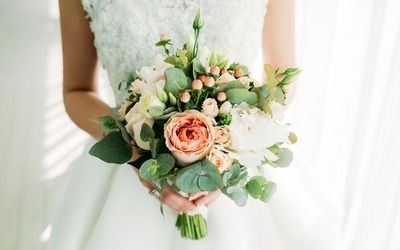 Braut hält einen Blumenstrauß mit pastellfarbenen Rosen und Eukalyptusblättern.