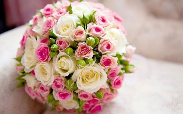 Romantischer Brautstrauß mit rosa und weißen Rosen auf einem Kissen.