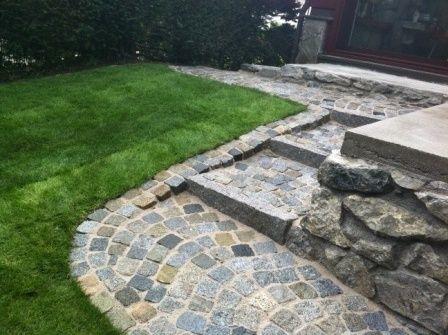 Neu gestalteter Gartenbereich mit neuem Rasen und gepflasterten Treppe