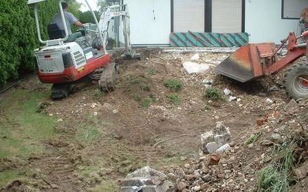 Baustelle im Garten mit Minibagger, Erdarbeiten und vorbereiteter Fläche für Neugestaltung.