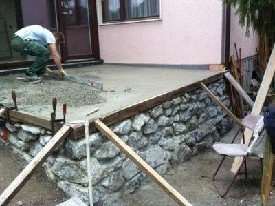 Handwerker glättet eine neu gegossene Betonfläche für eine Terrasse.
