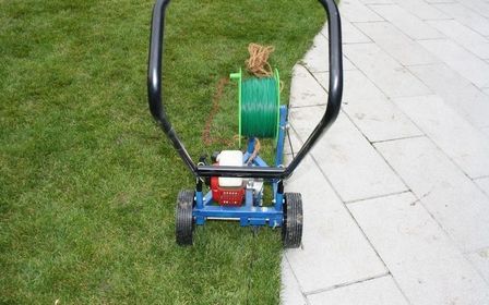 Gartengerät mit grünem Schlauch auf einer Rasenfläche, bereit zur Nutzung.
