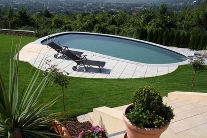 Runde Poollandschaft mit zwei Liegen und mediterraner Bepflanzung.