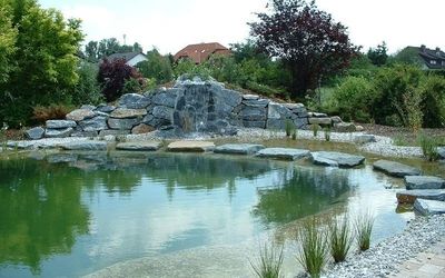 Schwimmteich mit Felsenlandschaft und Wasserfall.