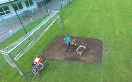 Pflege einer Sportanlage mit einer Maschine auf einem Fußballfeld.