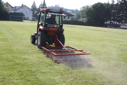 Aerifiziermaschine mit rotierenden Zinken lockert den Rasenboden auf.