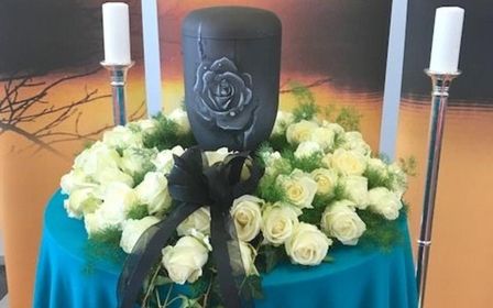 Trauerkranz mit gelben Blumen und grünen Blättern.