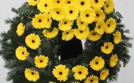 Großer Kranz mit gelben Blumen und grünen Blättern.