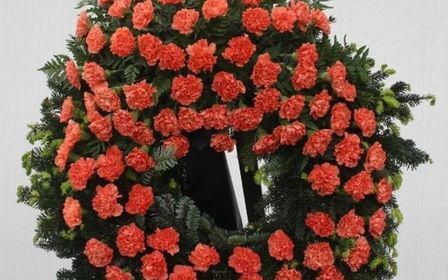 Runde Blumengestecke mit roten Nelken für eine Trauerfeier.
