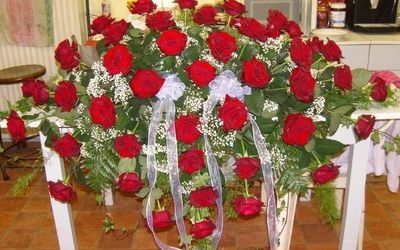 Kranz mit roten Rosen und weißen Akzenten für eine Beerdigung.